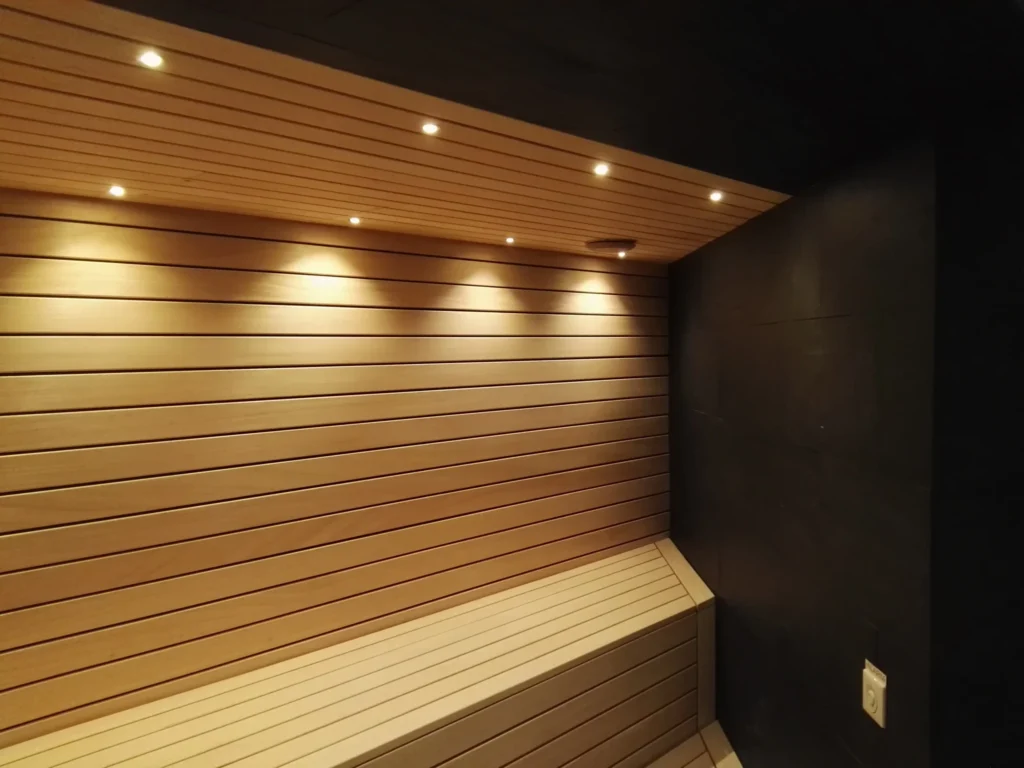 sauna fińska z drewnianą ławką, poziomymi panelami i punktowym oświetleniem sufitowym