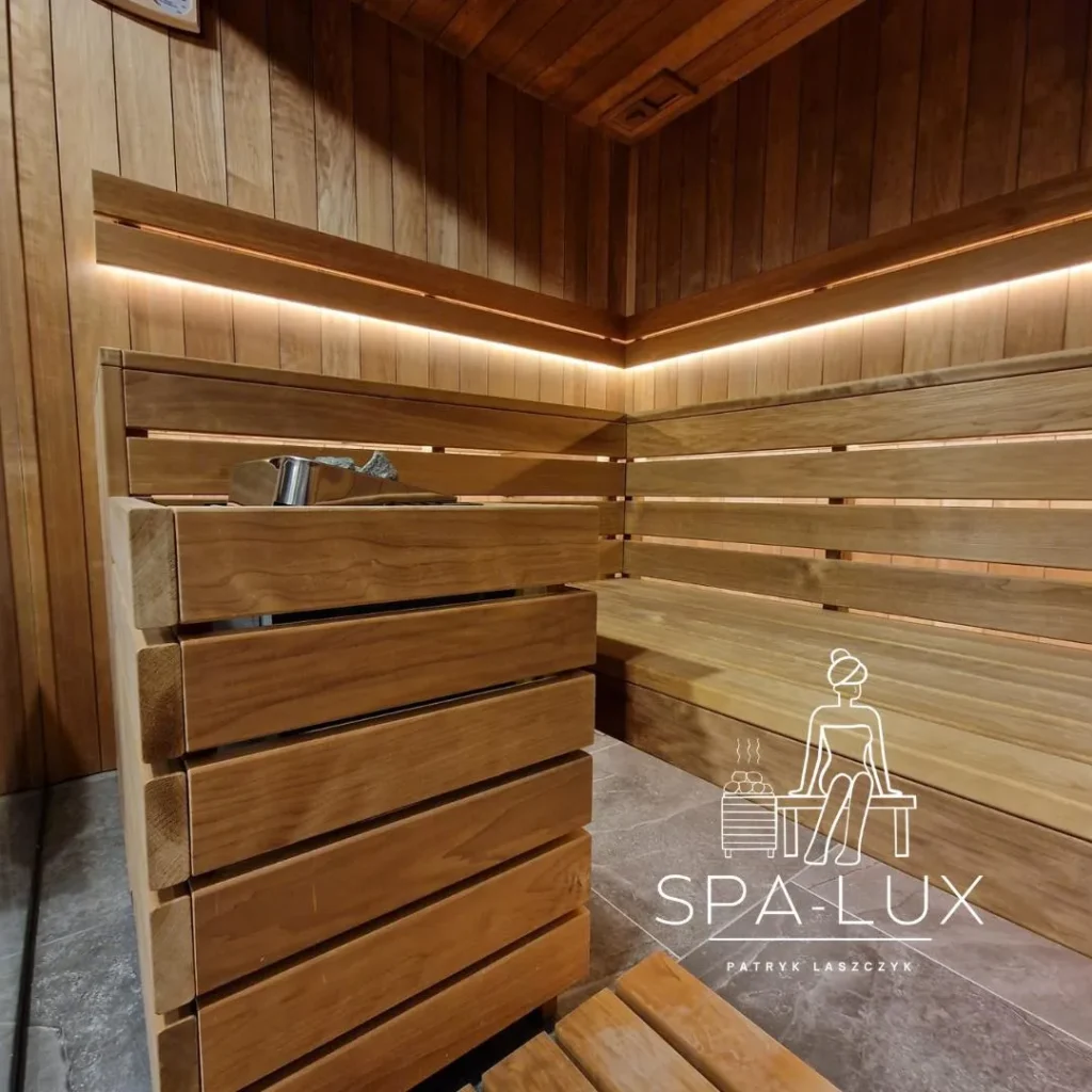 drewniana sauna fińska z osłoniętym piecem, narożnymi ławkami i ciepłym oświetleniem LED