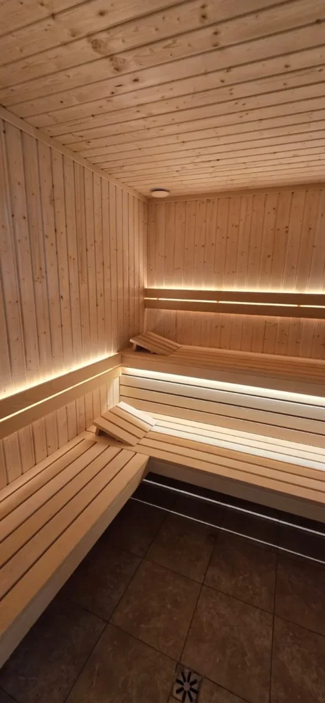 narożna sauna fińska z drewnianymi ławkami i ciepłym oświetleniem LED