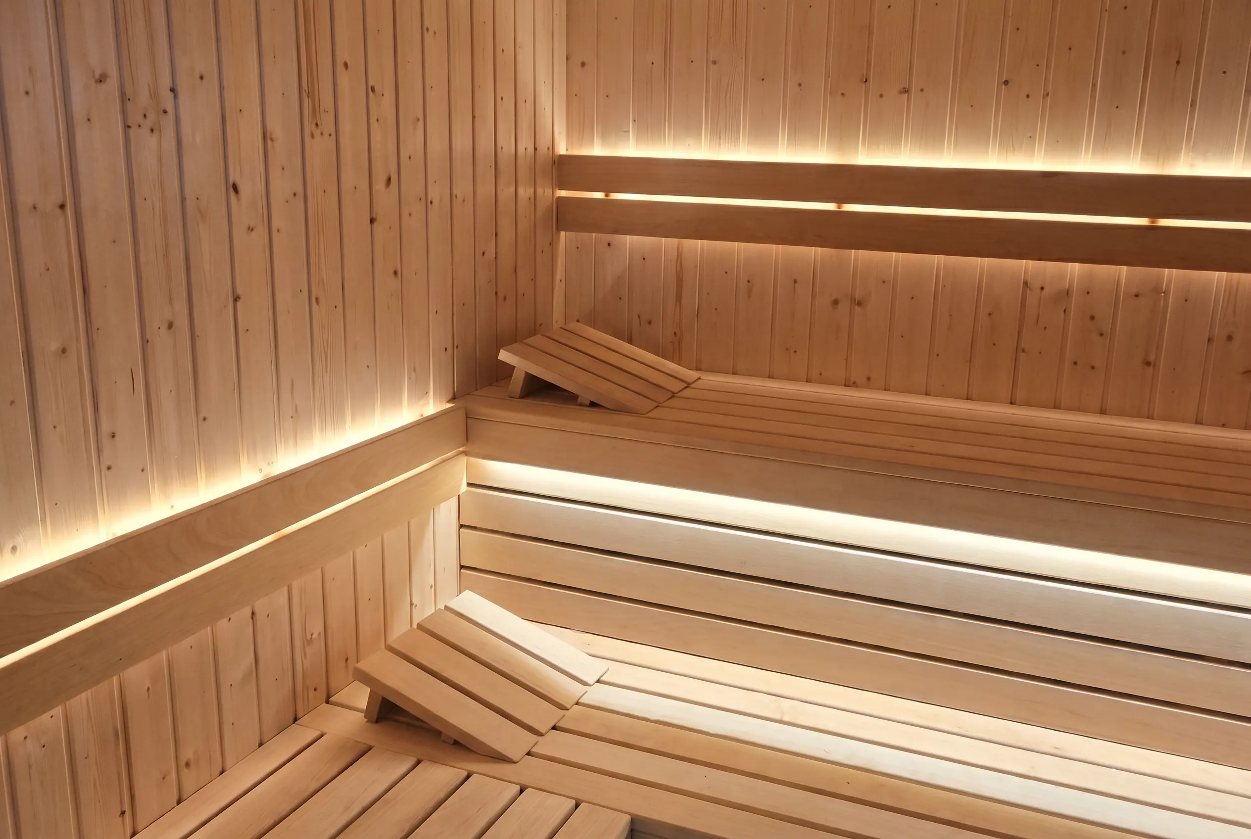 drewniana sauna fińska z ławkami, zagłówkami i ciepłym oświetleniem LED