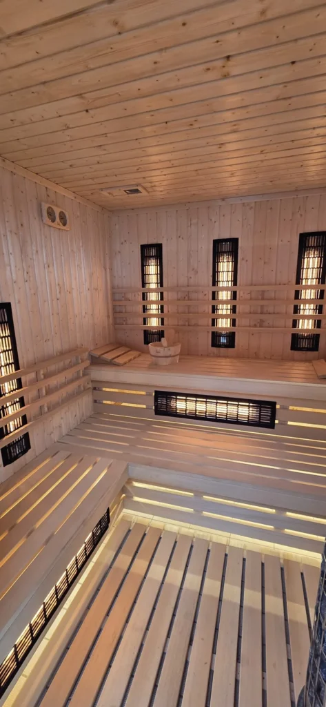 sauna infrared z jasnego drewna, promiennikami i podświetlanymi ławkami w strefie wellness